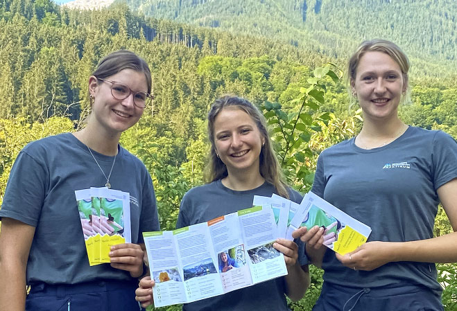 Das Bild zeigt drei Teenager-Mädchen mit Flyers des Sommerferienprogramms im Nationalpark Berchtesgaden - Foto: Nationalpark Berchtesgaden